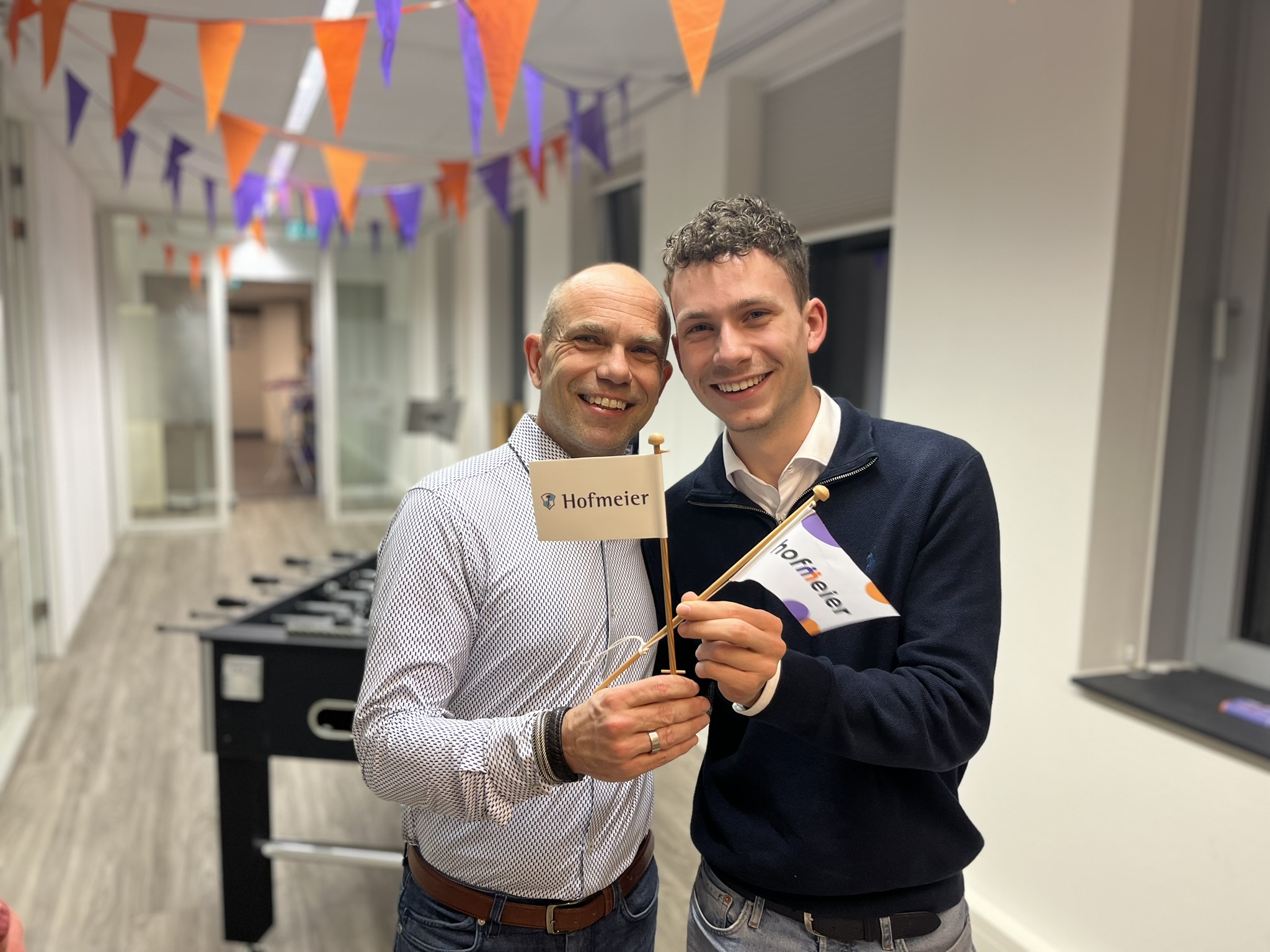 Mathijs en vader Marco houden vlaggetjes vast met oude en nieuwe logo